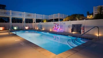 A swimming pool with a white deck and a covered area with a railing.