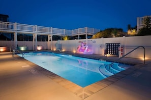 A swimming pool with a white deck, a lifeguard stand, and a poolside lounge area. - Oceanfront Free EV charger & GolfCart, Pool (Ocean Isle Beach)