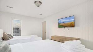 Ett hotellrum med två sängar, en byrå i trä, en platt-TV och ett fönster med persienner.