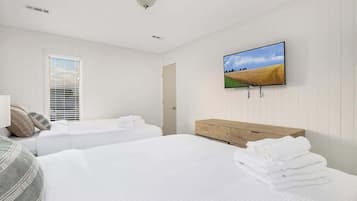 A hotel room with two beds, a wooden dresser, a flat-screen TV, and a window with blinds.