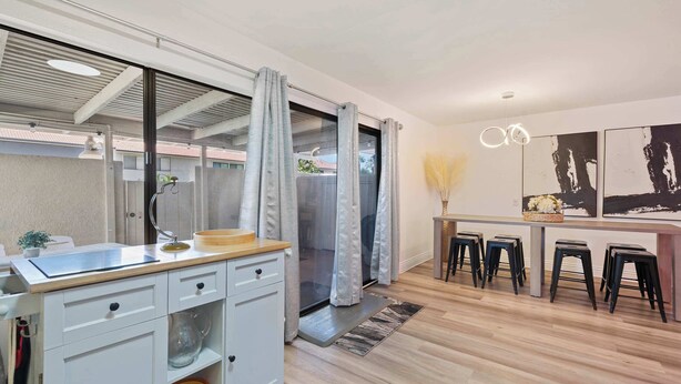 A modern kitchen with a large island, sliding glass doors, and a dining area with stools.