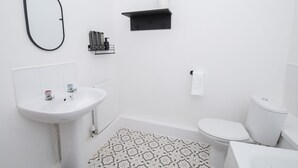 Une salle de bain moderne avec un lavabo blanc, des toilettes et un tapis à motifs.