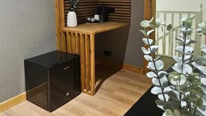 Une pièce avec un bureau en bois, une armoire noire et une plante en pot.