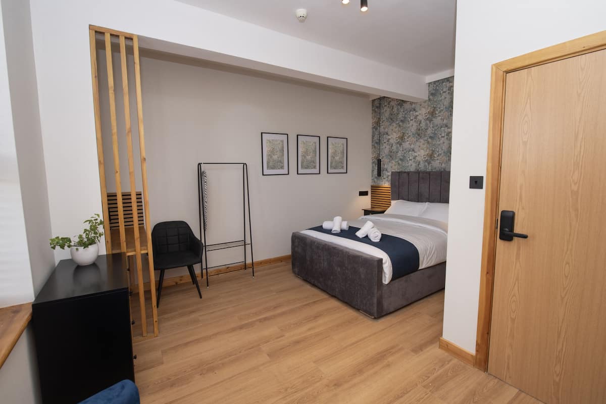 A modern bedroom with a bed, a desk, a chair, and a potted plant.