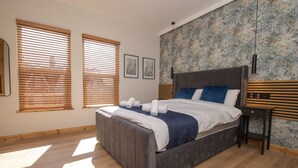 Une chambre à coucher avec un lit, un plancher en bois et de grandes fenêtres.