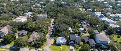 An aerial view of a residential area with houses, roads, and a beach in the background.
