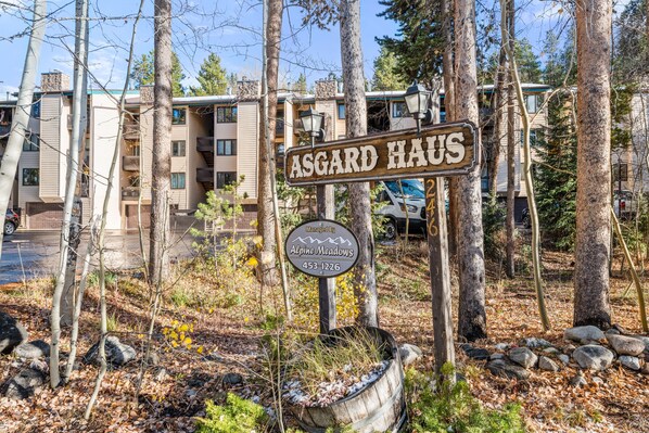 A sign for Asgard Haus with a contact number and a logo for Alpine Meadows.