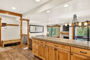 Una cocina moderna con armarios de madera, encimera de granito y un amplio ventanal con vistas a zonas verdes.