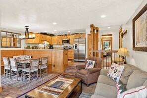 A spacious living area with a sofa, a coffee table, and a dining table with chairs.