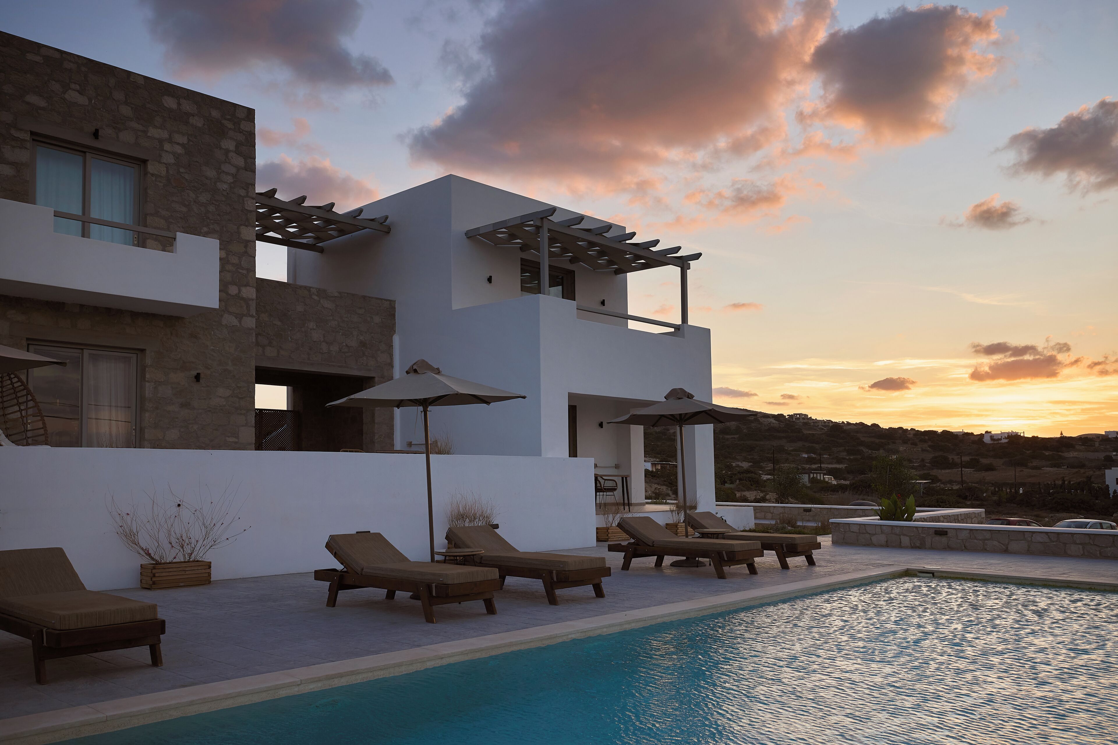 A modern villa with a pool, sun loungers, and a pergola.