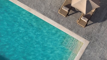 Una piscina al aire libre de temporada, sombrillas