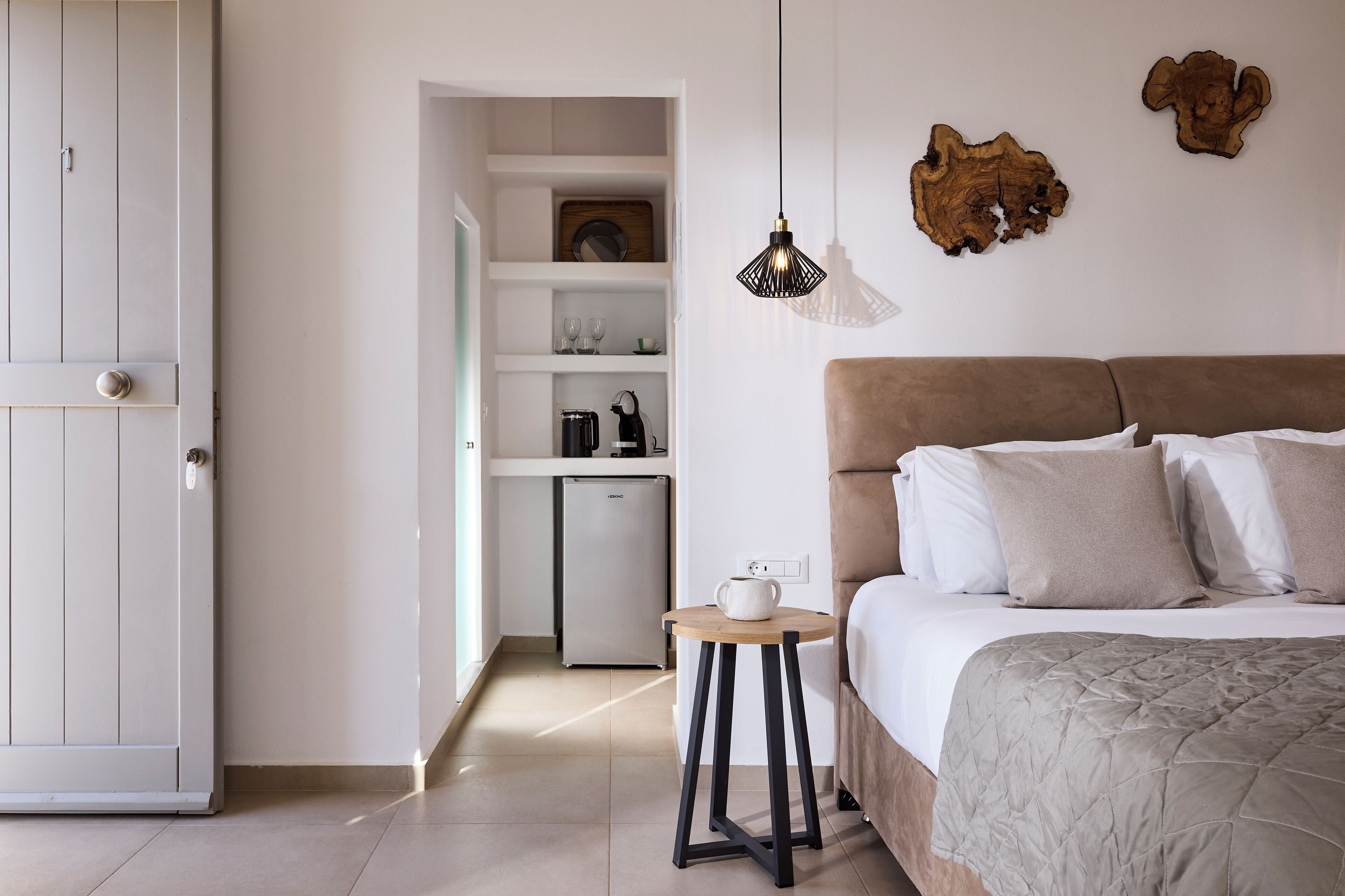 A bedroom with a bed, bedside table, and a small kitchenette.