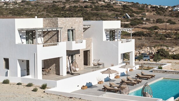 A modern villa with a pool, outdoor seating, and a view of the surrounding landscape. - Kedros Milos Suites (Milos)