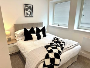 A bedroom with a bed, bedside table, lamp, and a window with blinds. - Host & Stay | Copper Box (Crosby)
