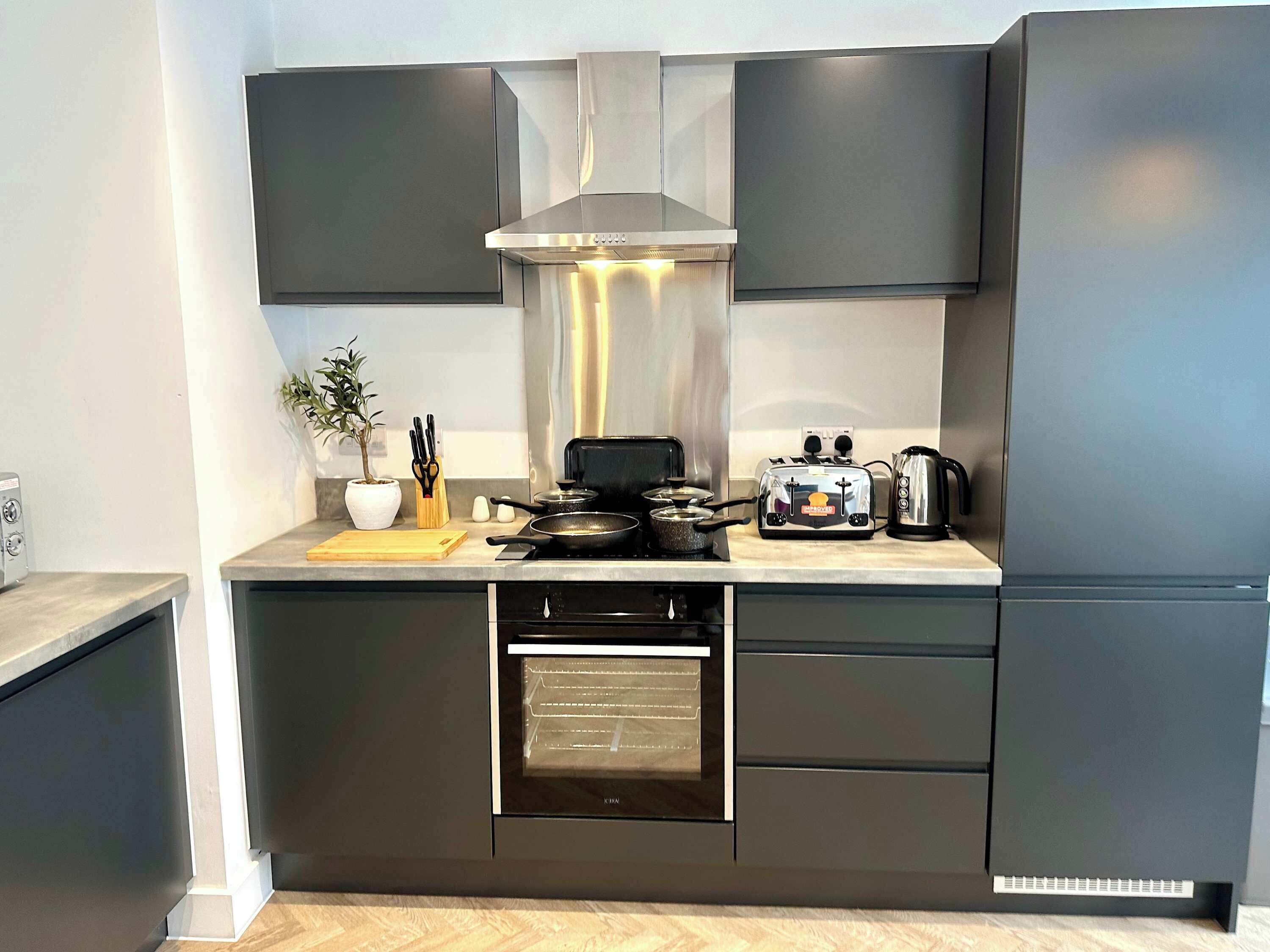 Een moderne keuken met donkere kastjes, een ingebouwde oven, een kookplaat en een broodrooster.
