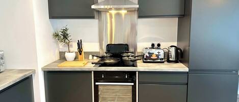 A modern kitchen with dark cabinetry, a built-in oven, a stove, and a toaster.