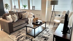 Un soggiorno moderno con un divano, un tavolino e una TV su un mobile.