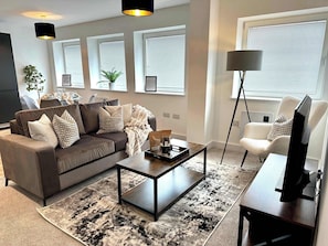 A modern living room with a sofa, coffee table, and a TV on a stand. - Host & Stay | Copper Box (Crosby)