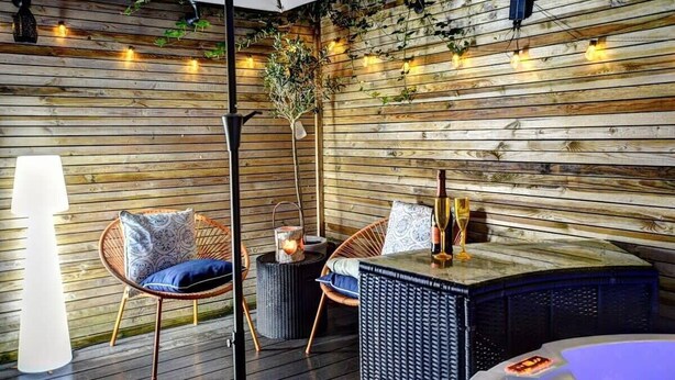 A cozy outdoor seating area with wooden walls, string lights, and wicker furniture. - Host & Stay | Bedford Place Hideaway (Brighton and Hove)