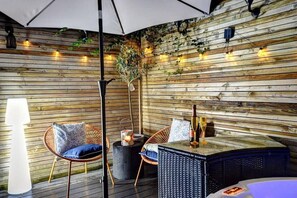 Un espacio al aire libre acogedor con paredes de madera, luces colgantes y mobiliario de mimbre.