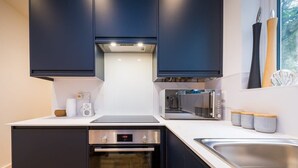 A modern kitchen with dark cabinets, a Bosch oven, a microwave, and a toaster. - Host & Stay | Osbourne Rest (Brighton and Hove)