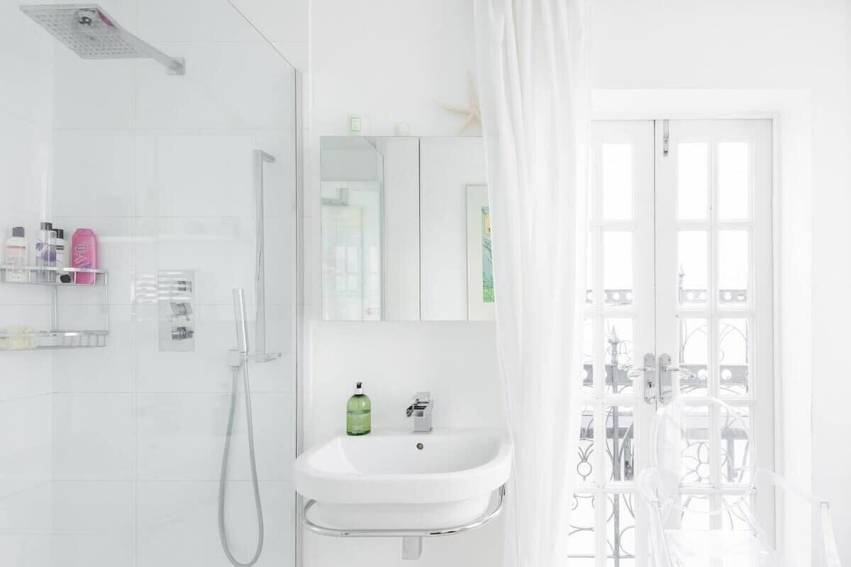 Un baño moderno con ducha, lavamanos y un espejo grande.