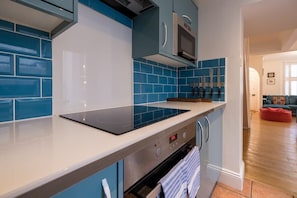 A modern kitchen with blue tiles, a black induction cooktop, and a built-in oven. - Host & Stay | Over Arches (Brighton and Hove)