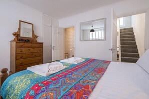 A bedroom with a bed, a wooden dresser, a mirror, and a staircase. - Host & Stay | Over Arches (Brighton and Hove)
