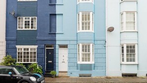 Une rangée de maisons à deux étages, avec des fenêtres à cadre blanc et une voiture noire garée devant.