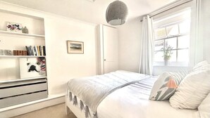 Una camera da letto con un letto, un armadio, una finestra con tende e una lampada a soffitto.