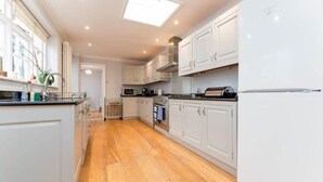 Una cucina moderna con mobili bianchi, forno integrato, microonde e un'ampia finestra sopra il lavello.