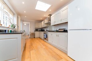 A modern kitchen with white cabinets, a built-in oven, a microwave, and a large window above the sink.