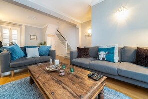 A living room with two grey sofas, a wooden coffee table, and a staircase in the background.