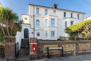 A multi-story residential building with a prominent entrance, a staircase, and a mailbox. - Host & Stay | Round Hill Apartment (Brighton and Hove)