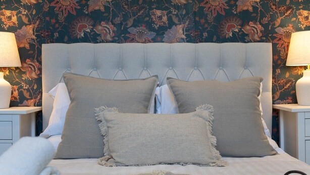 A bed with a tufted headboard, two side tables with lamps, and a floral wallpaper background. - Host & Stay | Round Hill Apartment (Brighton and Hove)