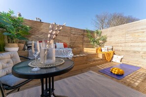A patio with a round table, chairs, a yoga mat, and a decorative plant arrangement. - Host & Stay | Round Hill Apartment (Brighton and Hove)