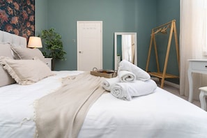 A neatly made bed with white linens and a beige throw blanket, a wooden dressing table with a mirror, a white dresser, and a wooden wardrobe. - Host & Stay | Round Hill Apartment (Brighton and Hove)
