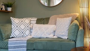 A green sofa with patterned pillows and a striped throw blanket. - Host & Stay | Round Hill Apartment (Brighton and Hove)