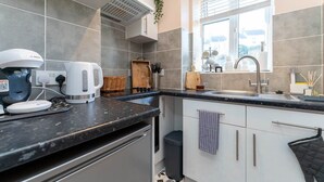 A modern kitchen with grey tiles, a built-in oven, a coffee machine, and a window with a view. - Host & Stay | Round Hill Apartment (Brighton and Hove)