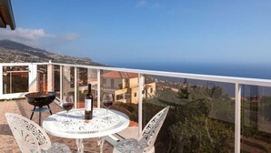 A balcony with a table set for two, a grill, and a bottle of wine. - Calheta Ocean View Retreat - Casa Santana (Estreito da Calheta)