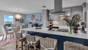 A modern kitchen with a large island, bar seating, and a view of the outdoors. - Waters Edge (Marathon)