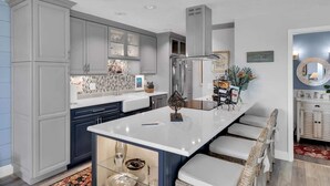 A modern kitchen with grey cabinets, a white island, and a built-in sink. - Waters Edge (Marathon)