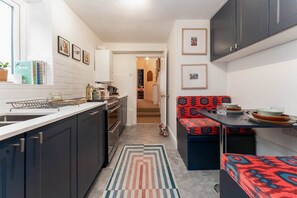 A compact kitchen with dark cabinets, a white countertop, and a patterned rug.