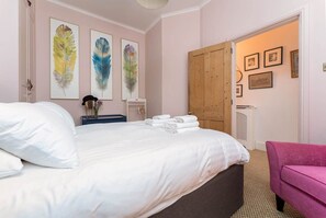 A bedroom with a bed, pillows, a nightstand, a dresser, a chair, and artwork on the walls. - Host & Stay | Stanford Opulence (Brighton and Hove)