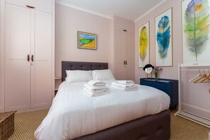 Una camera da letto con un letto, un armadio, un comodino e opere d'arte alle pareti.