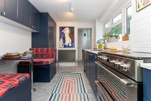 Una cucina compatta con mobili scuri, un'isola centrale con un cuscino decorato, un fornello e un termosifone.