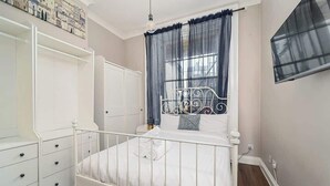 Un letto in metallo bianco con baldacchino, un'armadio bianco e un piccolo comodino.