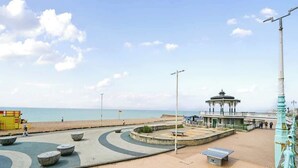 Una passeggiata costiera con un gazebo, panchine e vista sul mare.
