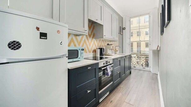 Una cucina moderna con forno a microonde, fornello e forno. Si vede una finestra con vista sugli edifici.