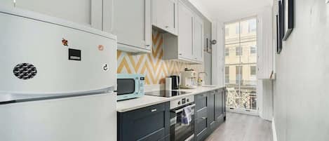 A modern kitchen with a microwave, stove, and oven. There is a window with a view of buildings outside.